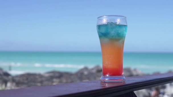 Prachtige cocktail in een glazen glas staat tegen de oceaan — Stockvideo