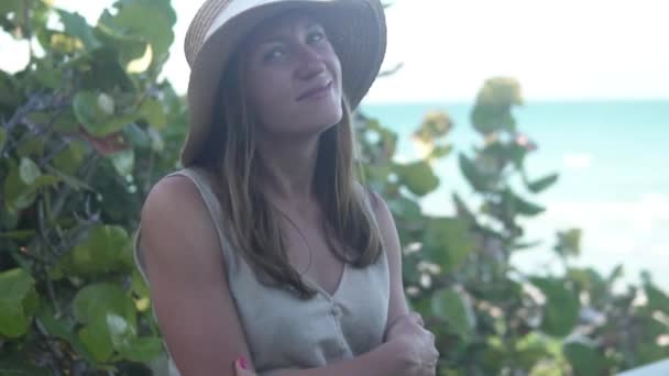 Kobieta w kapeluszu stoi przy wejściu na plażę i śni, — Wideo stockowe