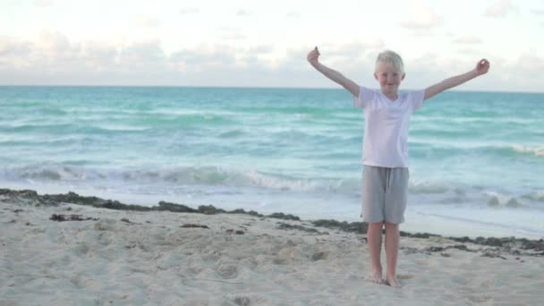 Мальчик-блондин делает руки сердце на голове — стоковое видео