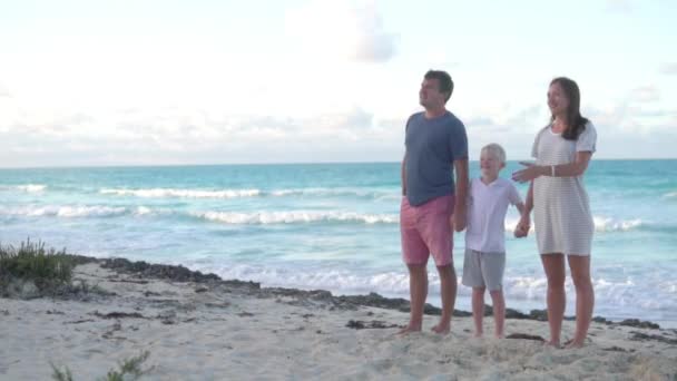 La familia feliz está junto al mar y se coge de la mano — Vídeo de stock