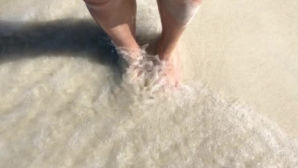 Vrouwen voeten staan op de stranden, golven wassen hun voeten. — Stockvideo