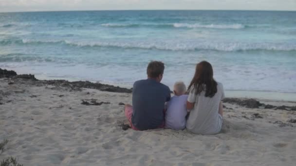 Rodina s dítětem sedí na pláži — Stock video
