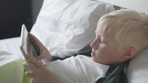 Piękny blond chłopiec leży w łóżku — Wideo stockowe