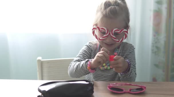 Забавная маленькая девочка красит губы помадой — стоковое видео