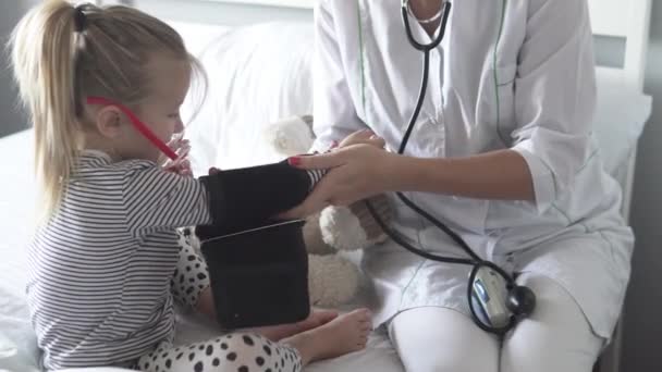 The doctor measures the pressure of the little girl in the hospital — 비디오