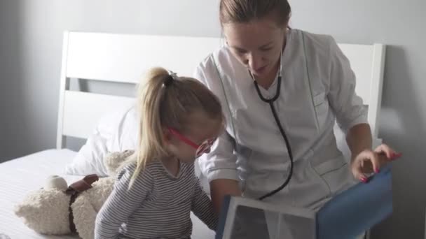 Doktorn visar flickan en bild av lungorna efter lunginflammationen. — Stockvideo