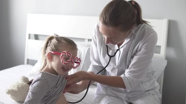 El médico escucha a la niña con un estetoscopio — Vídeo de stock