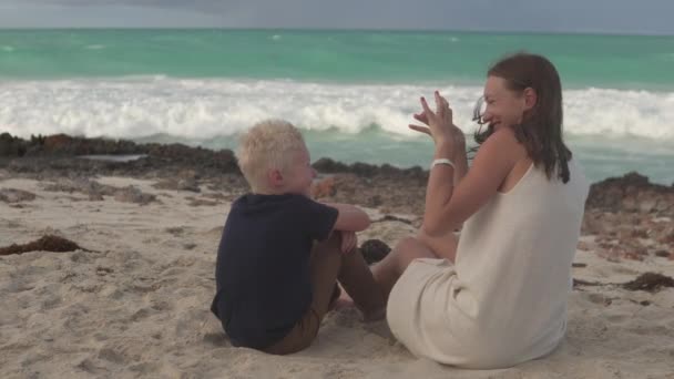 Mamá y su hijo rubio divertido hablando con la playa — Vídeos de Stock