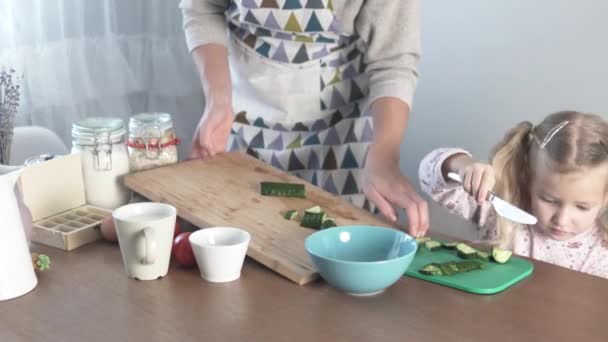 Anne kızına evde sebze salatası yapmayı öğretiyor. — Stok video