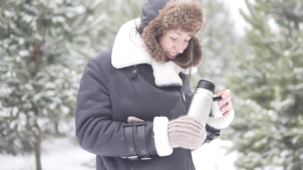 Frozen woman pours warm tea from thermos while walking through winter — Stock Video