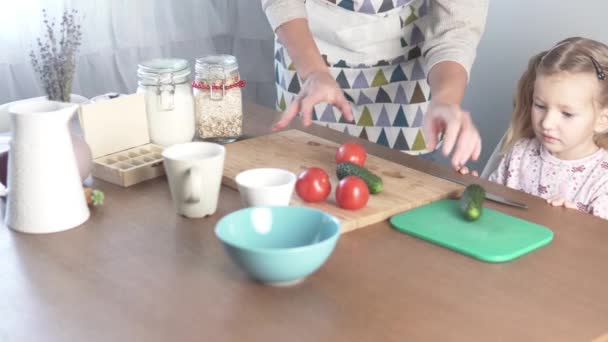 Mom and daughter prepare a salad of tomato and cucumbers — Stock Video