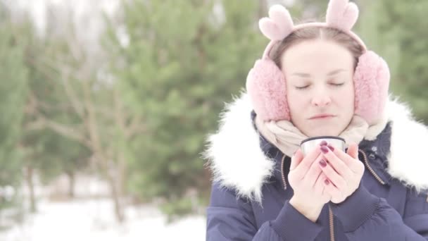 Una mujer bebe té caliente mientras camina por el parque de invierno — Vídeos de Stock