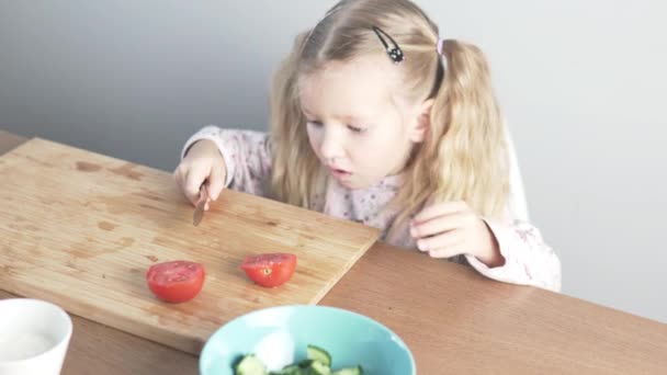 Cute little girl cuts a tomato — Stock Video