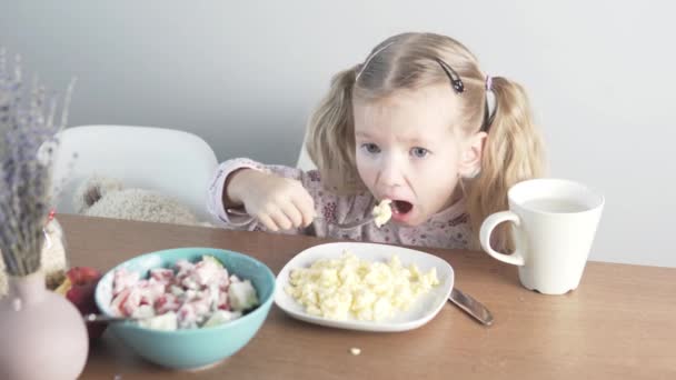 Menina come omelete em casa na cozinha — Vídeo de Stock