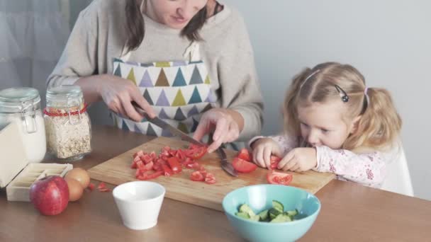Meine Tochter und meine Mutter schneiden Tomaten für Salat — Stockvideo