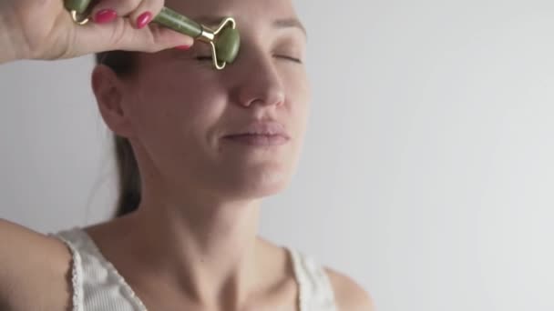 Женщина массирует лицо от морщин специальным роликом для век — стоковое видео