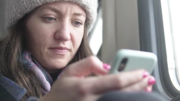 Een vrouw belt een bericht in een mobiele telefoon in een trein — Stockvideo