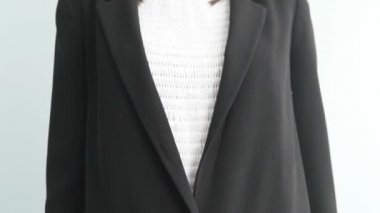 Ceketli bir kadın elini göğsünün hemen altına koyar.