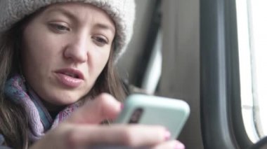 A woman writes a message in the phone while riding 