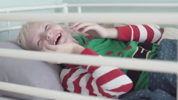 Счастливый ребенок лежит в постели в больнице — стоковое видео