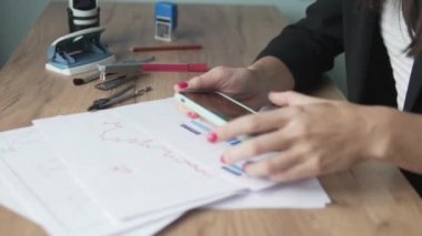 İşyerindeki bir kadın çizelgeleri kontrol edip sayıyor. 
