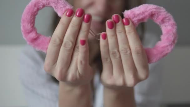 A woman holds pink handcuffs — Stock Video