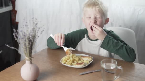 Den blonda pojken äter hemma med pasta och köttbullar — Stockvideo