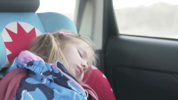 A beautiful little girl sleeps in a car in a car seat — Stok video