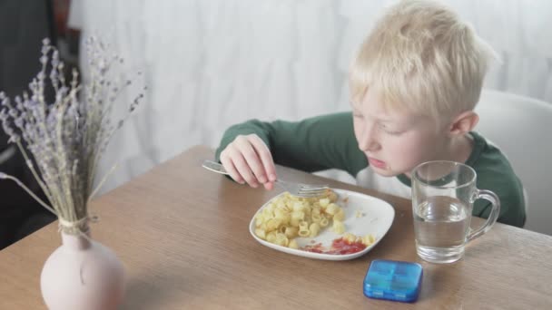 Мальчик ест макароны с фрикадельками дома на обед — стоковое видео