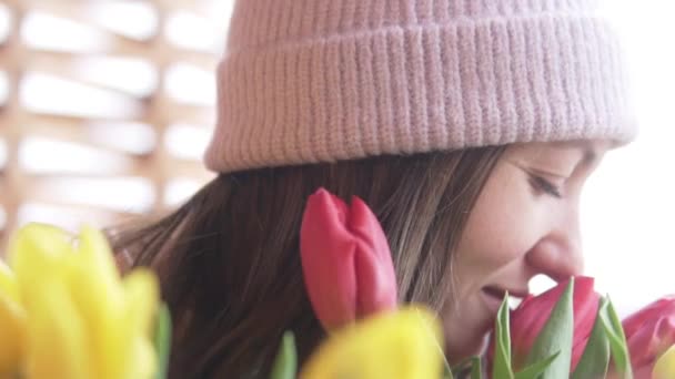 Una hermosa mujer huele un ramo de tulipanes donados en un día de mujeres — Vídeos de Stock
