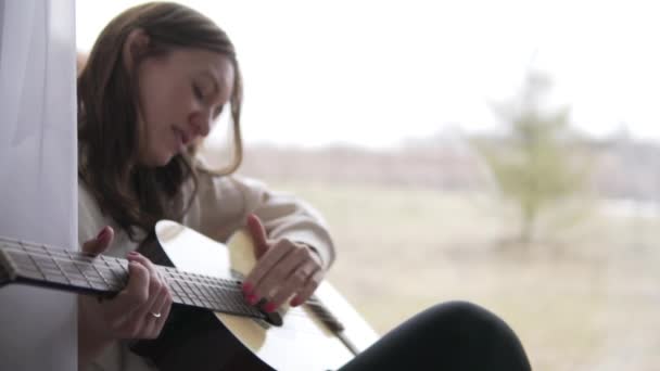 Uma mulher bonita toca guitarra. — Vídeo de Stock