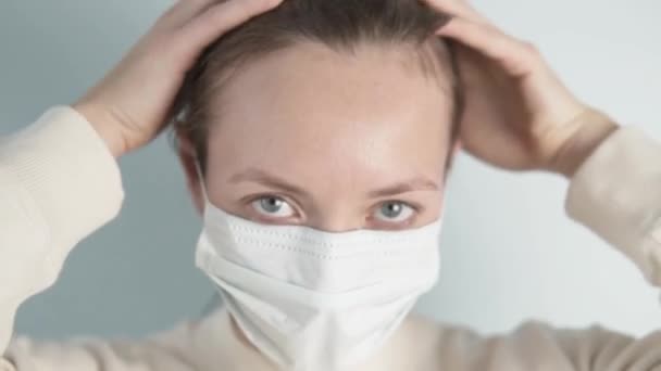 Een vrouw in quarantaine in een medisch masker spreidt haar haar uit — Stockvideo