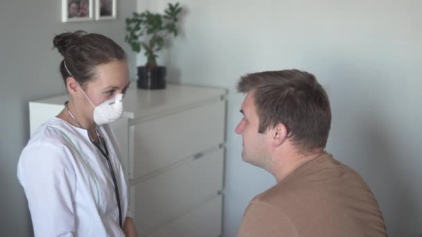 Доктор в маске разговаривает с пациентом и прощается с ним по-модному — стоковое видео