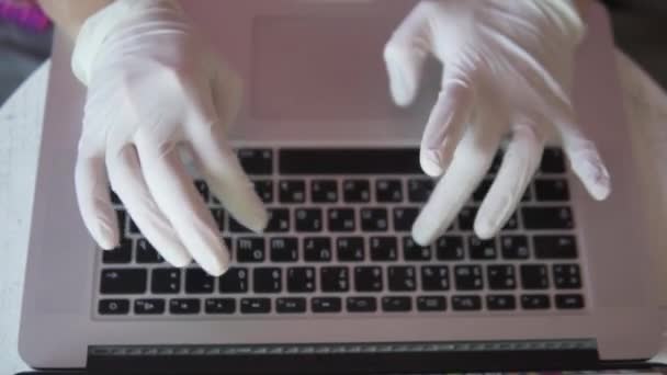 A woman prints a laptop keyboard in silicone gloves during the epidemic — Stock Video