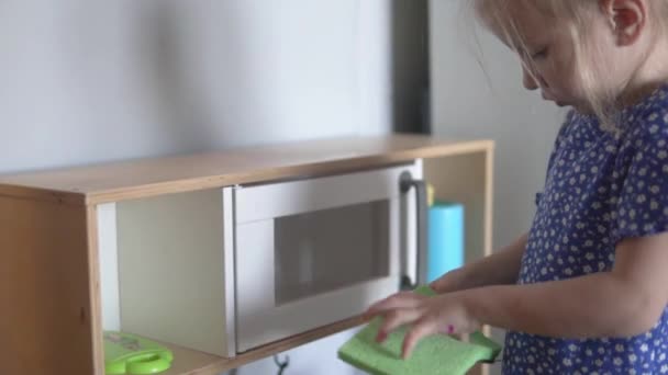 Een klein meisje ruimt op in de kinderkeuken.. — Stockvideo