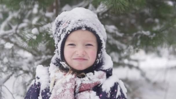 Um close-up de uma menina na neve durante uma caminhada de inverno — Vídeo de Stock