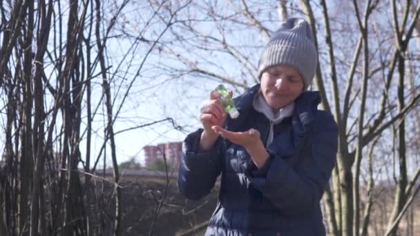 Podczas spaceru kobieta rozmazuje ręce żelem przeciwbakteryjnym. — Wideo stockowe