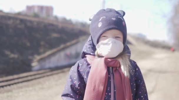 Un primer plano de una niña usando una máscara junto al ferrocarril — Vídeos de Stock