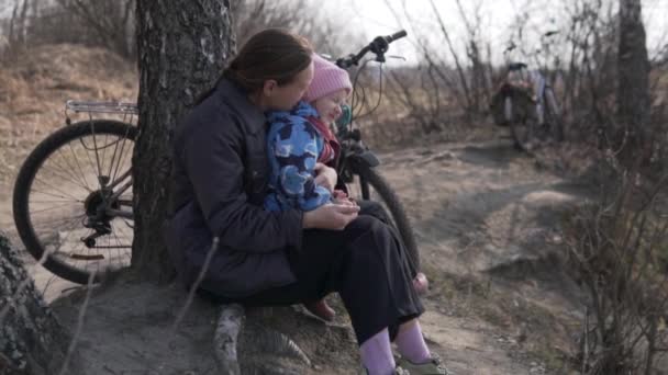 Máma a dcerka sedí v lese u řeky samy a povídají si. — Stock video