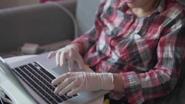 Eine Frau arbeitet von zu Hause aus mit Silikonhandschuhen am Computer. — Stockvideo
