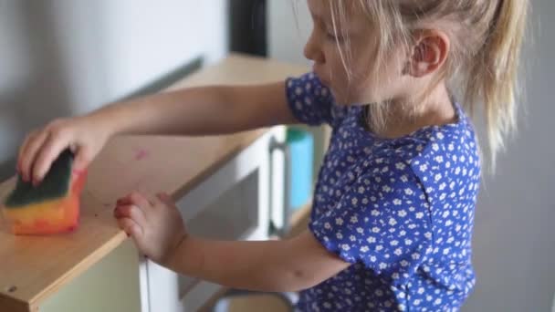 Funny little girl cleans up in her toy kitchen. — Stock Video