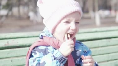 Küçük kız baharda sokakta şeker yiyor.