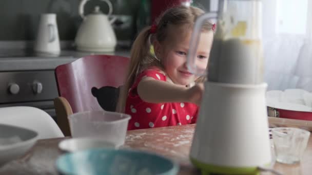 Das kleine Mädchen schaltet zu Hause in der Küche den Mixer ein. — Stockvideo