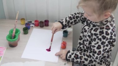 Küçük bir kız kendini izole ederken balkonda resim yapıyor.