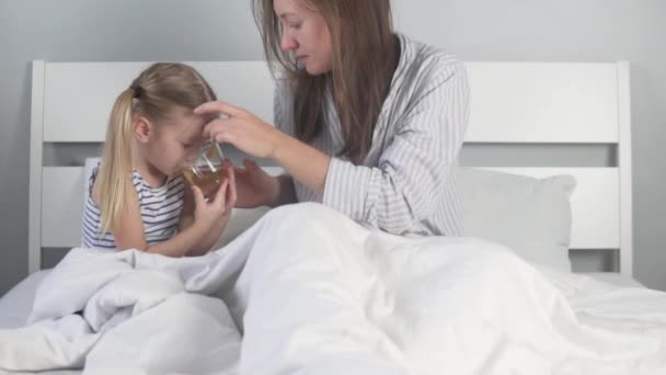 Fürsorgliche Mutter gibt ihrer Tochter warmen Tee mit Zitrone — Stockvideo