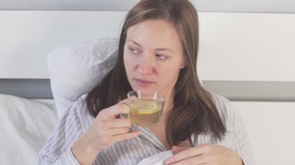 Chora kobieta pije herbatę z cytryną w domu w łóżku — Wideo stockowe
