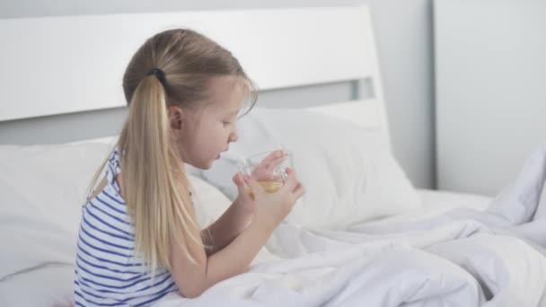 Koncepcja. Miła dziewczynka pije herbatę z cytryną w szpitalu. — Wideo stockowe