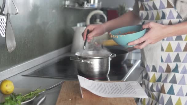 Uma mulher cozinha sopa de acordo com uma receita — Vídeo de Stock