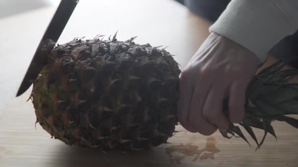 Un gros ananas est coupé avec un couteau dans la cuisine — Video