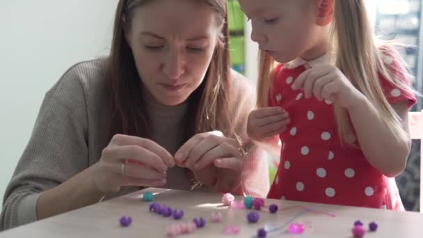 Mamá e hija hacen una pulsera a mano — Vídeo de stock